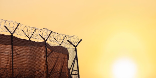 clôture de fil de fer barbelé symbolisant la protection sur le fond du ciel au coucher du soleil avec une place pour le texte