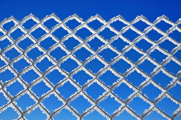 Photo une clôture de fil recouverte de gel contre le ciel bleu.