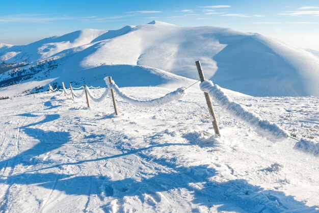 Clôture avec glace et neige dans le village alpin d'hiver. Paysage de montagne