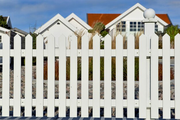 Photo la clôture d'un jardin en bois blanc devant les fenêtres sur la façade blanche d'une maison