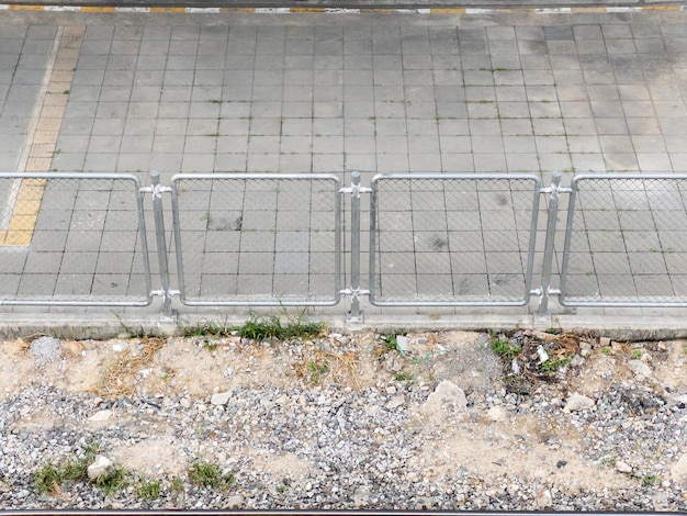 La clôture métallique le long de la voie ferrée et du trottoir pour protéger les piétons