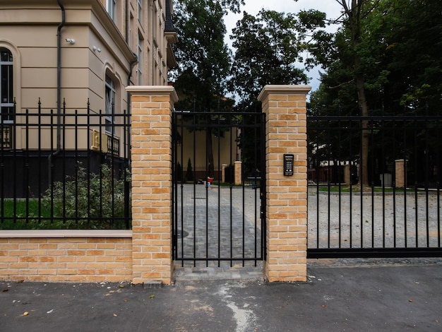 clôture métallique noire avec porte et brique de façade jaune