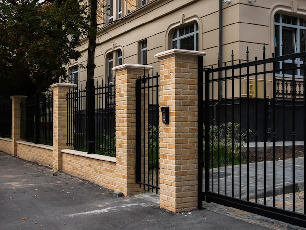 clôture métallique noire avec porte et brique de façade jaune
