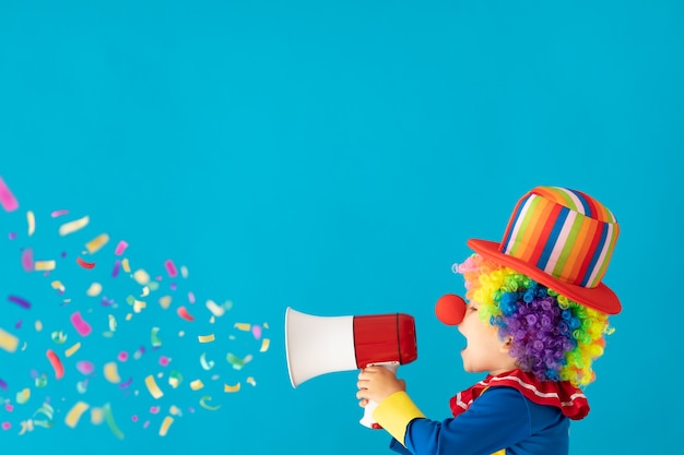 Clown drôle d'enfant contre le mur bleu.