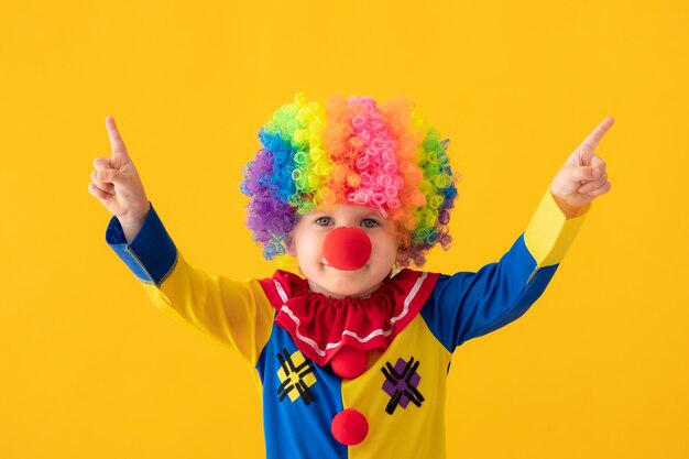 Photo clown drôle d'enfant contre le mur jaune.