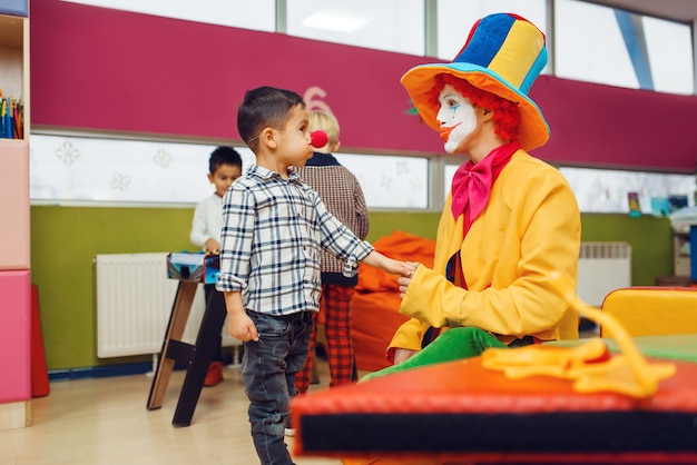 Un clown drôle et un petit garçon au nez rouge jouent ensemble.