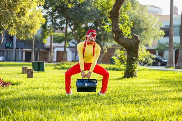 Clown essayant de déplacer une valise dans un parc