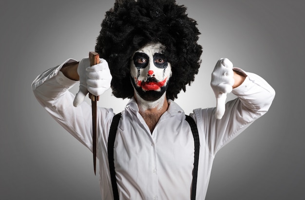 Clown tueur avec couteau faisant un mauvais signal sur fond texturé