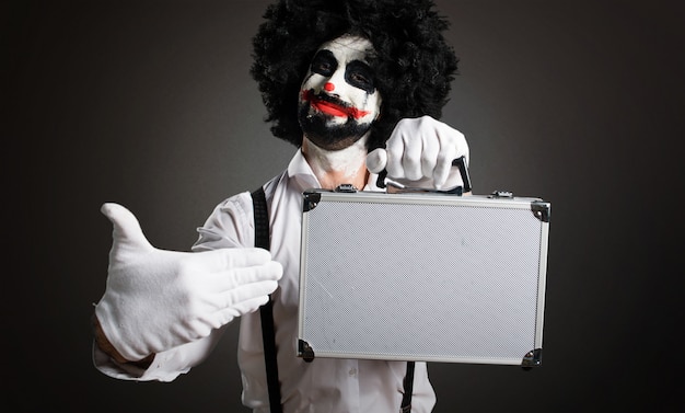 Clown tueur tenant une mallette sur fond texturé