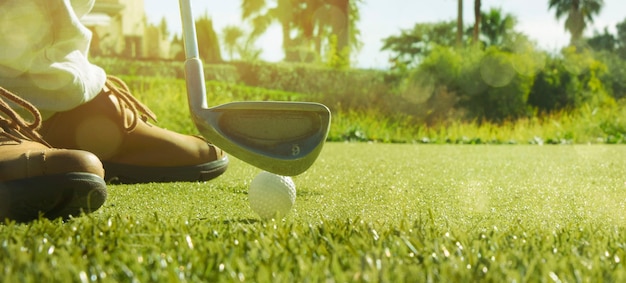 Club de golf et balle de golf dans l'herbe au lever du soleil.