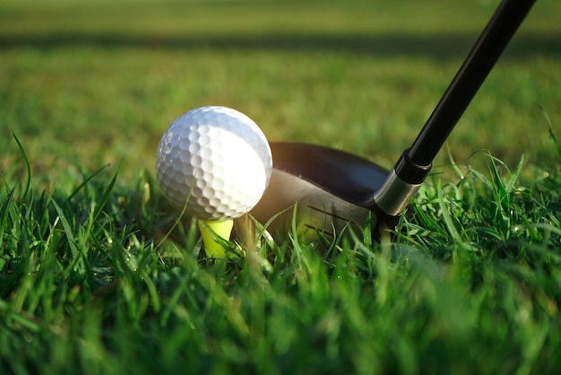 Photo club de golf et balle de golf à proximité dans le champ d'herbe avec le coucher du soleil