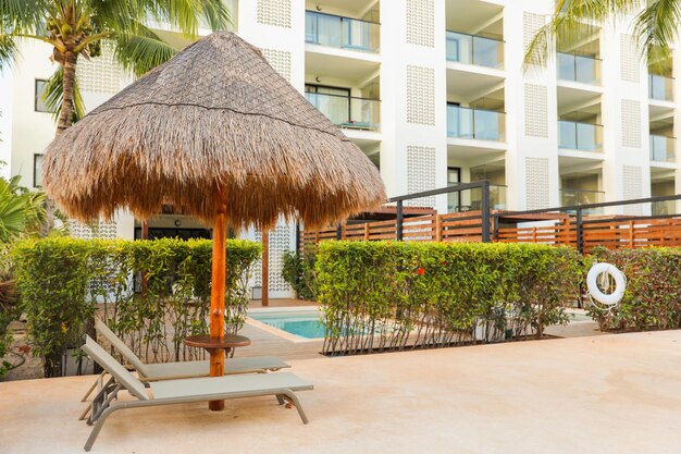 Un club de plage avec une chaise longue et un parasol en chaume