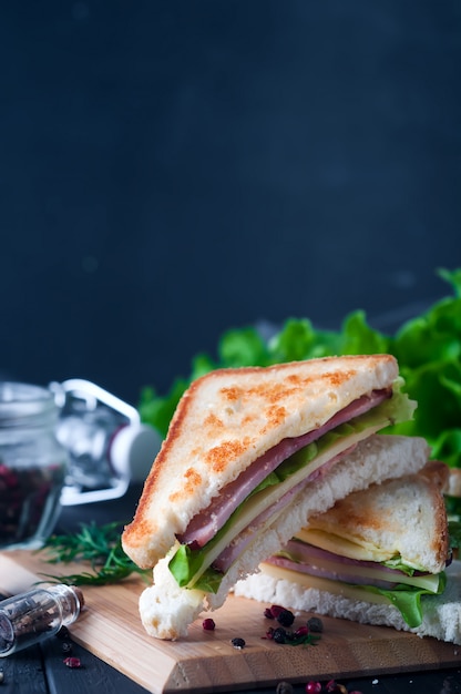 Club sandwich avec une salade sur une plaque de bois