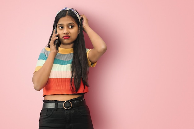Clueless Confus jeune fille asiatique indienne posant isolée parler avec un téléphone portable se grattant la tête de frustration Maquette copie espace
