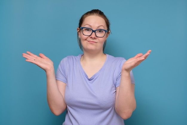 Clueless young caucasian woman in glasses haussant les épaules impuissant