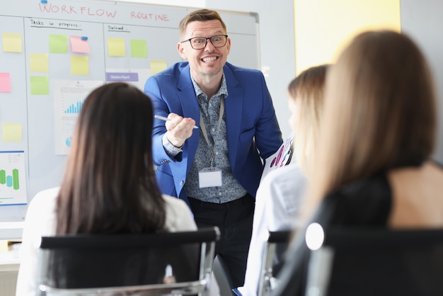 Coach d'affaires avec des lunettes expliquant les informations aux auditeurs dans l'auditoire