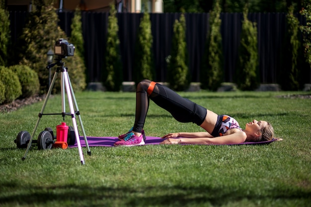 Coach de fitness femme enregistrement vidéo blog par caméra sur la formation d'entraînement au jardin