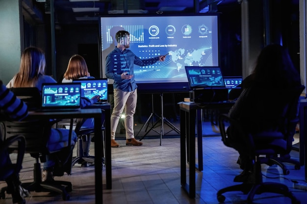 Coach intelligent Formateur d'affaires masculin est contre le projecteur avec des données enseignant les gens