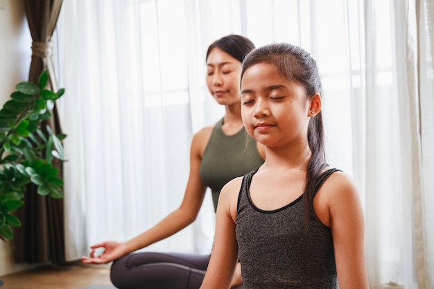 Coach de yoga femme enseignant à une fille la pose de yoga et l'exercice avec son chien à la maison