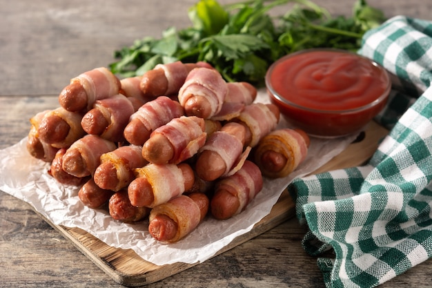 Cochon dans des couvertures Saucisses enveloppées de bacon fumé sur table en bois