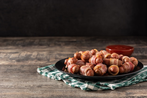 Cochon dans des couvertures Saucisses enveloppées de bacon fumé sur table en bois