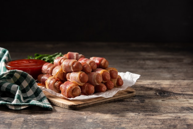 Cochon dans des couvertures Saucisses enveloppées de bacon fumé sur table en bois