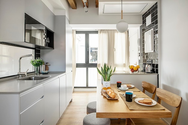 Photo cocina en pequeno apartamento de alquiler vacacional con el desayuno servido en la mesa del office con cafe bollos y tostadas
