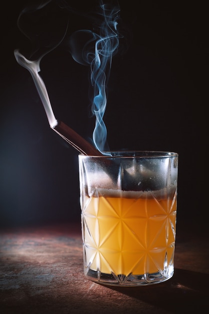 Cocktail d'alcool avec des bâtons de cannelle fumants
