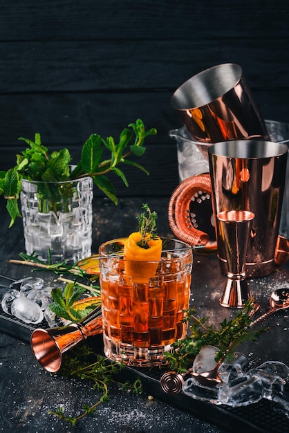 Cocktail d'alcool Negroni glace à l'orange sur un fond de bois noir