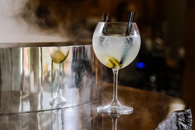 Cocktail d'alcool transparent avec de la chaux et de la glace sur le fond fumé