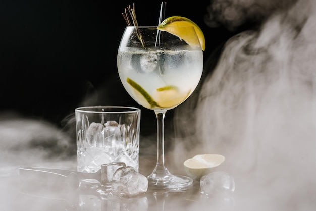 Cocktail d'alcool transparent avec de la chaux et de la glace sur le fond fumé