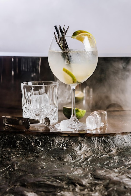 Cocktail d'alcool transparent avec de la chaux et de la glace sur le fond fumé