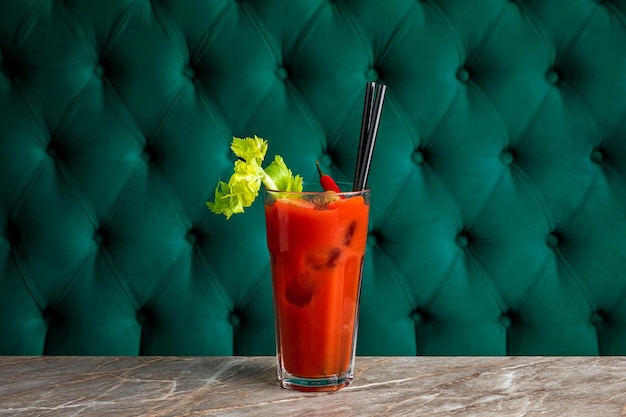 Cocktail alcoolisé Bloody Mary avec du jus de tomate servi dans un verre highball garni de céleri et de piment