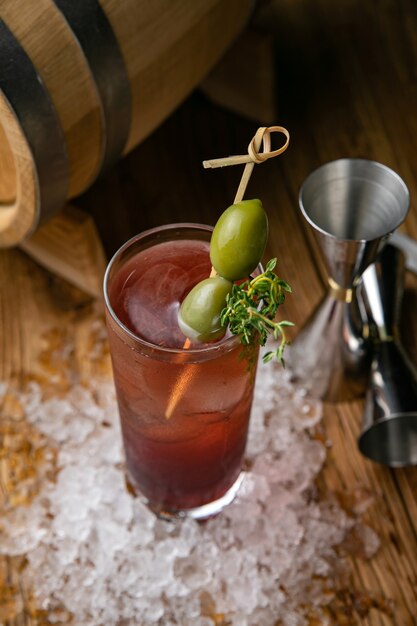 Cocktail alcoolisé avec de la glace, des olives sur une table en bois