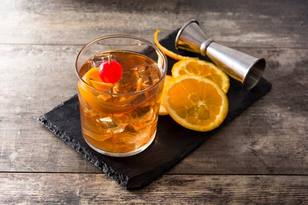 Cocktail à l'ancienne avec orange et cerise sur table en bois