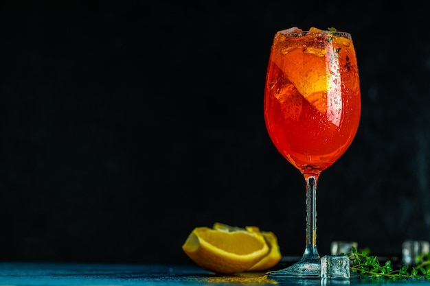 Cocktail aperol spritz dans un grand verre à vin avec des gouttes d'eau sur fond sombre Cocktail d'alcool d'été avec des tranches d'orange Cocktail italien aperol spritz sur ardoise Boisson à la mode