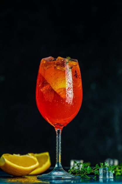 Cocktail aperol spritz dans un grand verre à vin avec des gouttes d'eau sur fond sombre Cocktail d'alcool d'été avec des tranches d'orange Cocktail italien aperol spritz sur ardoise Boisson à la mode