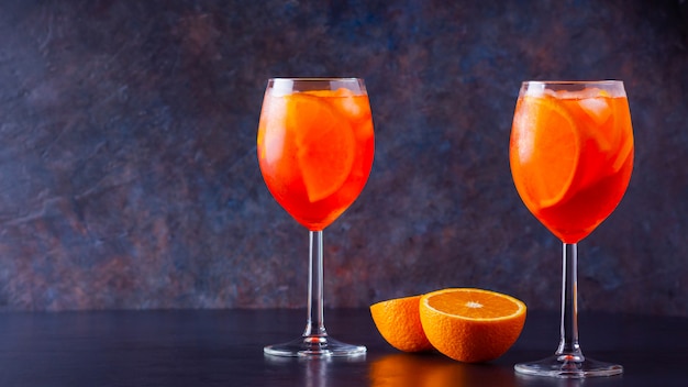 Cocktail Aperol spritz sur fond sombre. Deux verres d'aperol spritz avec des tranches d'orange. Cocktail d'été en verre.