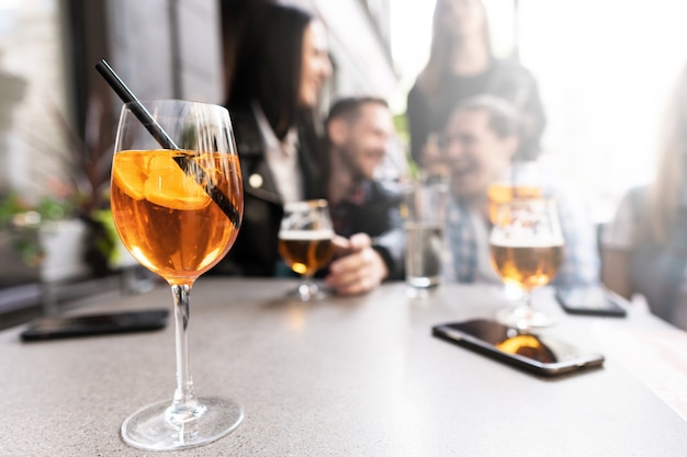 Cocktail Aperol Spritz sur une table avec un groupe d'amis assis