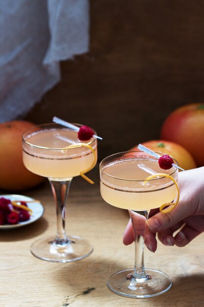 Cocktail au champagne avec jus de pamplemousse, garni de zeste et de framboises. Style rustique.