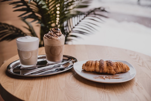 cocktail au chocolat avec crème glacée. Cappuccino et croissant au café. café du matin, petit déjeuner dans un café confortable près de la fenêtre