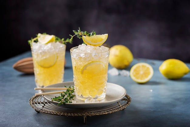 Cocktail au citron, timo et glace pilée sur le fond sombre, concept de bar et image de mise au point sélective