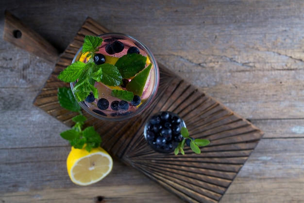 Cocktail aux bleuets - Mojito avec citron frais, citron vert, glace et menthe sur fond en bois ancien Vue de dessus, espace copie