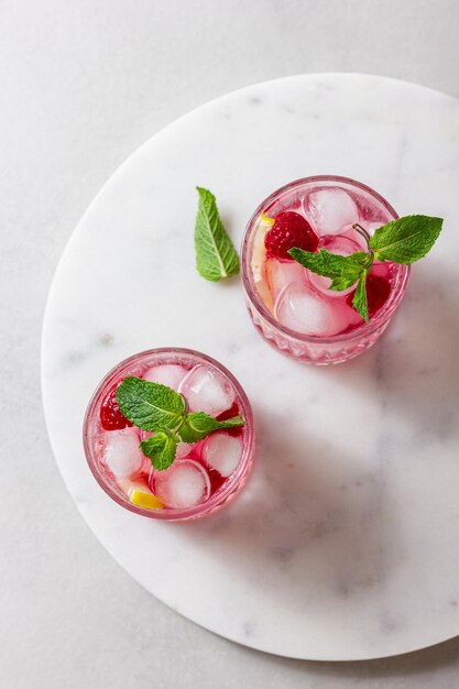 Cocktail aux framboises avec de la glace dans un verre sur un fond clair