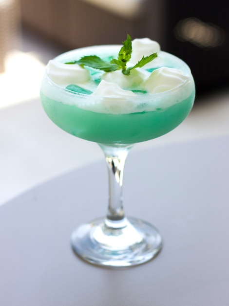 Cocktail bleu dans un beau verre avec crème glacée et feuilles de menthe verte