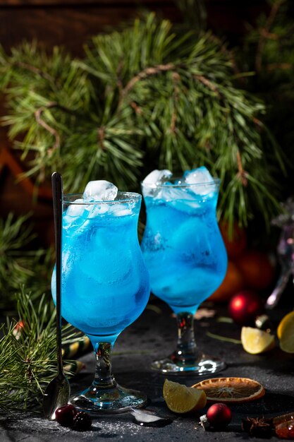 Cocktail bleu dans un grand verre avec de la glace et des tranches de citron sur un fond en bois