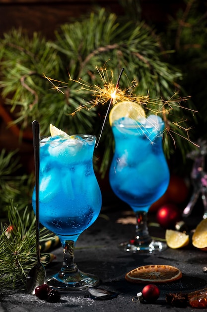 Cocktail bleu dans un grand verre avec de la glace et des tranches de citron sur un fond en bois