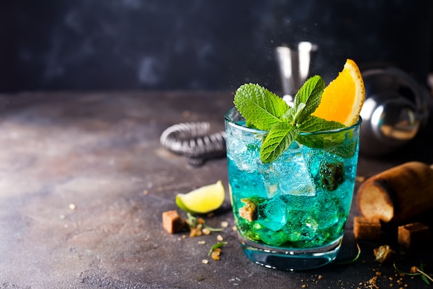 Cocktail bleu dans des verres avec glace, menthe et orange