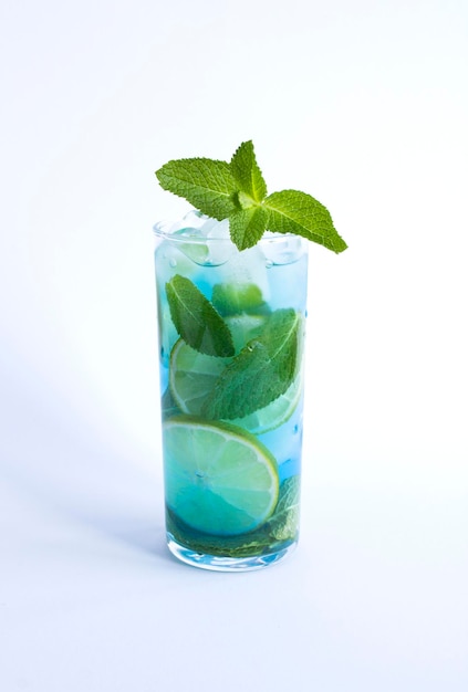 Cocktail bleu avec du citron vert et de la menthe dans le verre à boire sur fond blanc Emplacement vertical