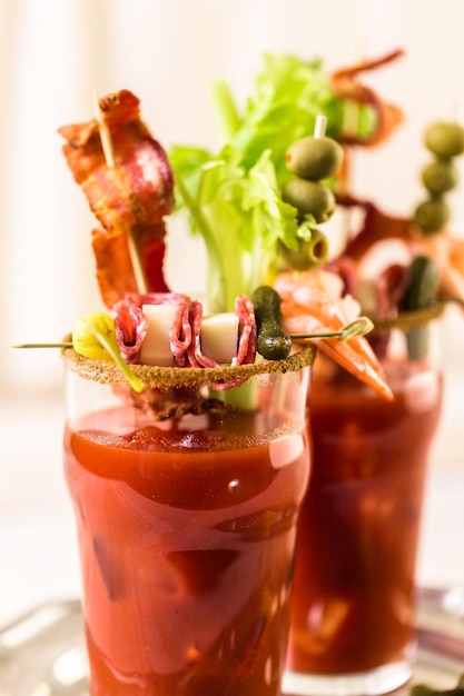 Cocktail Bloody Mary garni de bâtonnets de céleri, d'olives et de lanières de bacon.